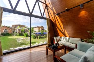 a living room with a large window and a couch at ELIVAAS 4 BHK Pvt Pool & Party Hall - Oakwood Cottages in Jaipur