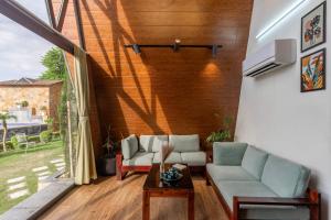 a living room with a couch and a table at ELIVAAS 4 BHK Pvt Pool & Party Hall - Oakwood Cottages in Jaipur