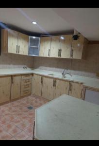 an empty kitchen with wooden cabinets and a sink at وحدات الشاطئ المفروشة in Jeddah