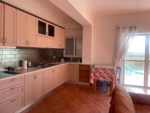 a kitchen with white cabinets and a table and a window at Anastasias apartments in Sarandë