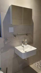 ein Badezimmer mit einem weißen Waschbecken und einem Spiegel in der Unterkunft The Cottage Unit in Kathu + 10 Fotos