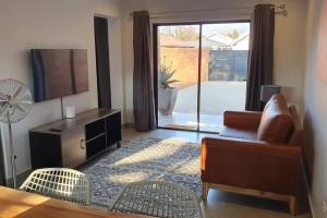 a living room with a chair and a couch and a window at The Cottage Unit in Kathu
