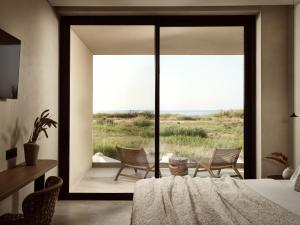 a bedroom with a bed and chairs and a large window at Mayamor Villas, sea view to Tsilivi beach in Tsilivi