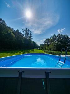 a large swimming pool with the sun in the sky at Szalejówka Domki in Kłodzko