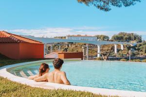 un uomo e una donna seduti su una tavola da surf in una piscina di The Lost Garden a Vila Nova de Gaia