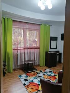 sala de estar con cortinas verdes y alfombra en Pensiunea Gil, en Predeal