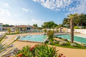 a swimming pool with palm trees and a resort at Camping Les Grenettes in Sainte-Marie-de-Ré