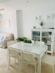 a white dining room with a white table and chairs at Espacioso apartamento en Barbate con Wifi in Barbate