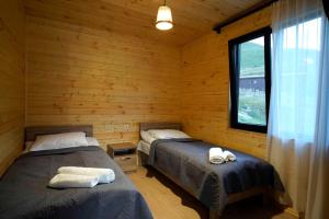 2 letti in una baita di tronchi con finestra di Ushguli Highland Cottage a Ushguli