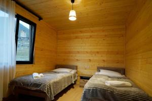sypialnia z dwoma łóżkami w chacie z bali w obiekcie Ushguli Highland Cottage w mieście Ushguli