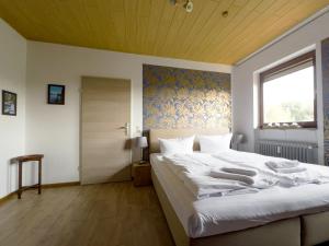 a bedroom with a large white bed with a wooden ceiling at Ferienwohnung Hexenstieg in Sankt Andreasberg