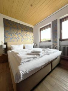 a bedroom with a large white bed with a wooden ceiling at Ferienwohnung Hexenstieg in Sankt Andreasberg