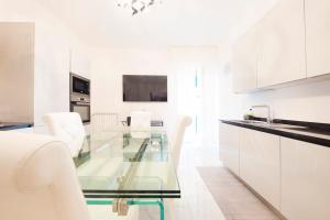 a white kitchen with a glass table and white chairs at Exclusive with Jacuzzi between Portofino and 5 Terre in Chiavari