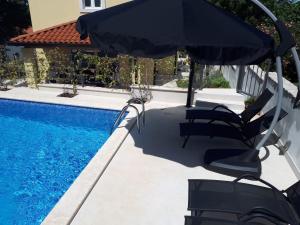 a swimming pool with two chairs and an umbrella at Ferienhaus mit Privatpool für 8 Personen ca 120 qm in Mugeba, Istrien Istrische Riviera in Mugeba