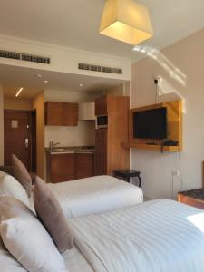 two beds in a hotel room with a kitchen at Big Ben Hotel Suites in Amman