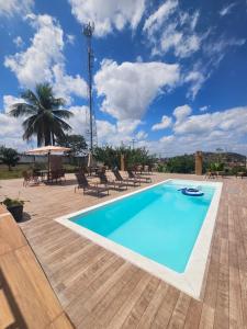 a swimming pool with chairs and a palm tree at Pousada Casa Bella in Itaberaba