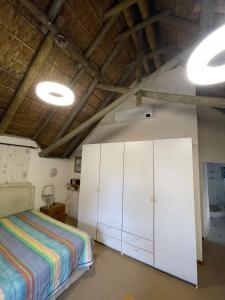 a bedroom with a bed and white cabinets at Plotsklaps Self Catering Cottage in Tokai