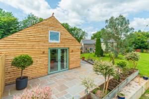 a home with a pitched roof and a patio at Self-contained cosy one bedroom holiday barn in Cowbridge