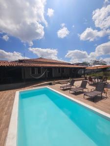 a swimming pool with chairs and a house at Pousada Casa Bella in Itaberaba +14 photos