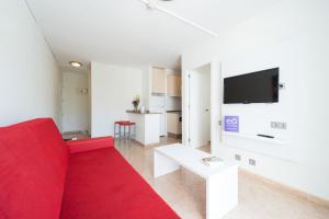 a living room with a red couch and a tv at eó Las Rosas in Playa del Ingles