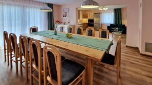a dining room and kitchen with a wooden table and chairs at Wisienka in Pstrągowa
