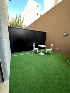 a patio with two chairs and a table and grass at Chic Apartments For Rent ave0-4 in Umm Uthainah