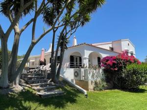Una casa blanca con palmeras y escaleras en un patio. en Villa Quatre Vents, en Punta Prima