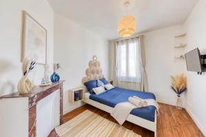 1 dormitorio con cama azul y chimenea en Appartement chic proche gare de Clamart + Netflix, en Malakoff