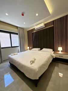 a bedroom with a large bed with two towels on it at Chic Apartments For Rent ave0-6 in Amman