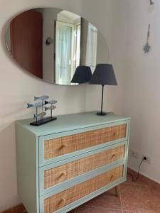 a dresser with a mirror and a lamp on it at Appartamento La Fontina in Marciana Marina