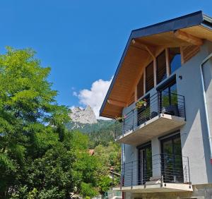 a building with a balcony with mountains in the background at La Fruitière de Vérel, logements modulables neufs, calmes, entre lac et montagne, max 11 personnes in Rovagny