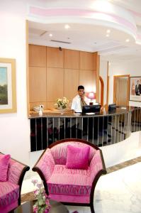 Ein Mann steht an einem Schreibtisch in einer Lobby mit einer rosa Couch in der Unterkunft Hotel la princesse in Tunis