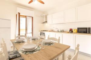 a kitchen with a wooden table and white cabinets at CA' DU GU' Free wifi - centrale in Carloforte