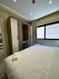 a bedroom with a large white bed and a window at Chic Apartments For Rent ave0-7 in Umm Uthainah