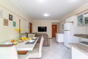 a kitchen and living room with a table and a couch at Confortável Apartamento a Poucos Minutos da Praia in Bombas
