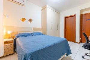 a bedroom with a blue bed and a desk at Confortável Apartamento a Poucos Minutos da Praia in Bombas