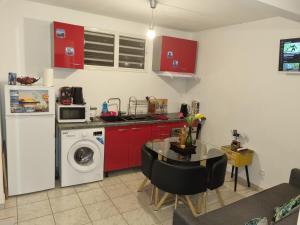 a kitchen with red cabinets and a table and a washing machine at Hibiscus et Miro in Ducos +6 photos