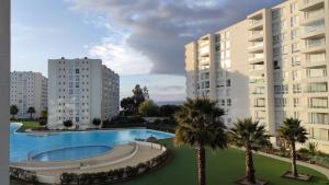 an apartment complex with a swimming pool and palm trees at Departamento en Papudo con acceso directo a la playa in Papudo