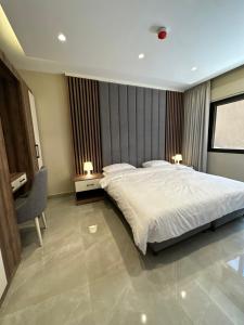 a bedroom with a large white bed and a chair at Chic Apartments For Rent ave0-9 in Amman