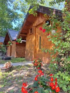 a wooden cabin with red flowers in front of it at Kamp Vodeni Ćiro in Setihovo