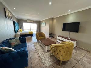 Una sala de estar con un sofá y un televisor. en Boat Yard Guest House, en Hartbeespoort
