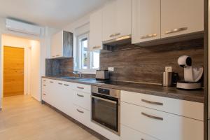 a kitchen with white cabinets and a wooden wall at Apartments Mandre in Mandre