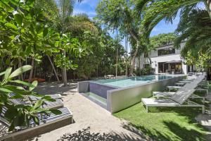 a swimming pool with chaise lounge chairs in a garden at The Waterhouse- Amazing Villa With Infinity Pool in Miami