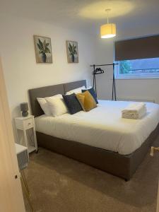 une chambre avec un grand lit avec des oreillers dessus dans l'établissement Homely 3-bed home Milton Keynes, à Simpson