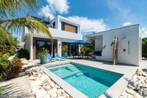 a villa with a swimming pool in front of a house at Grace Bay Vacation Villa in Long Bay Hills