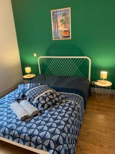 a bedroom with a bed with a green wall at Rue de la paix in Mont-de-Marsan