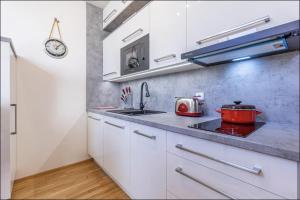 uma cozinha com armários brancos e uma panela vermelha no fogão em Minimalist's Dream - sunny cozy studio in New Town em Praga