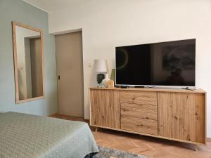 a bedroom with a flat screen tv on a wooden dresser at D422Apartman in Dunaújváros