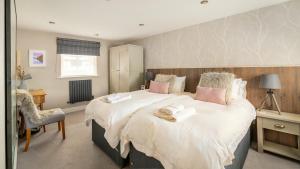 a bedroom with a large white bed with pink pillows at Derwentwater View in Portinscale