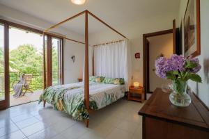 a bedroom with a canopy bed and a vase of purple flowers at Casa Salea in Castelveccana +82 photos